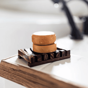 Image of a shampoo and conditioner bar on a wooden shower dish